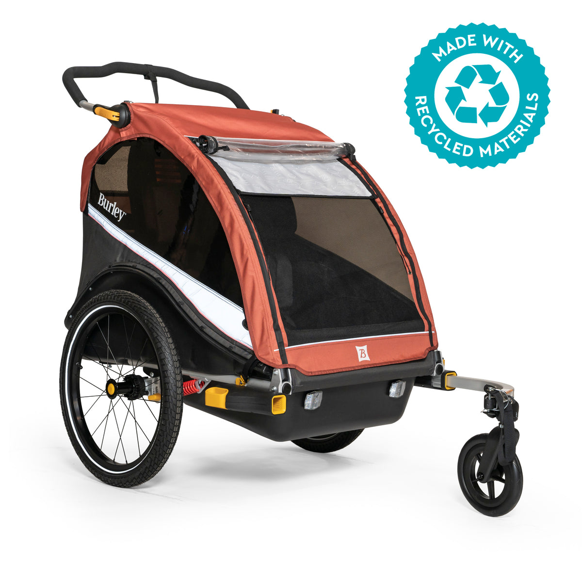 A brick red and black Cub X bike trailer and stroller for kids, featuring a durable plastic base, tinted side windows, and an adjustable suspension. The product is marked as made with recycled materials.