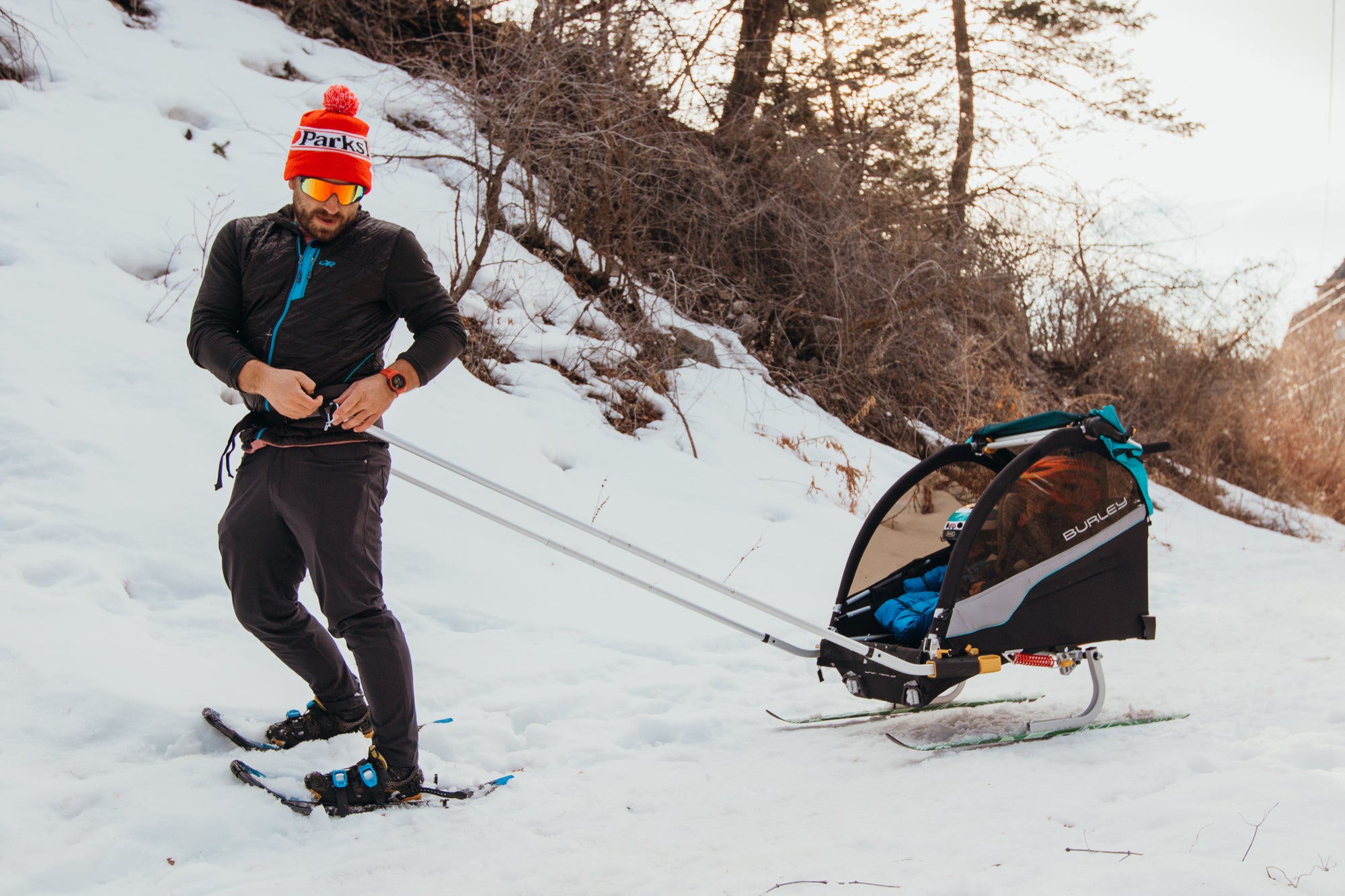 man clipping kids ski trailer to harness on his waist