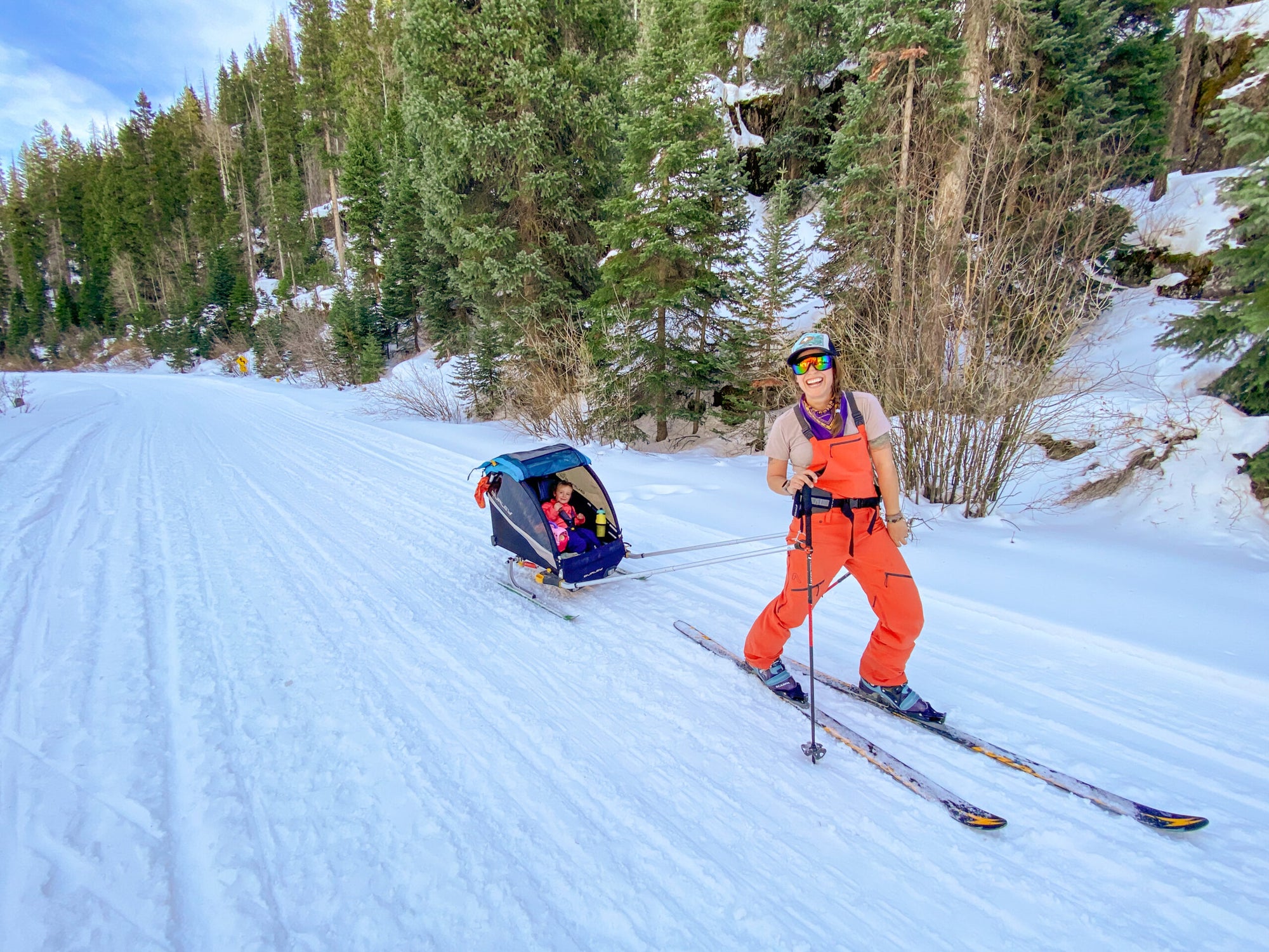 woman skiing with kids bike trailer converted to ski trailer attached around her waist