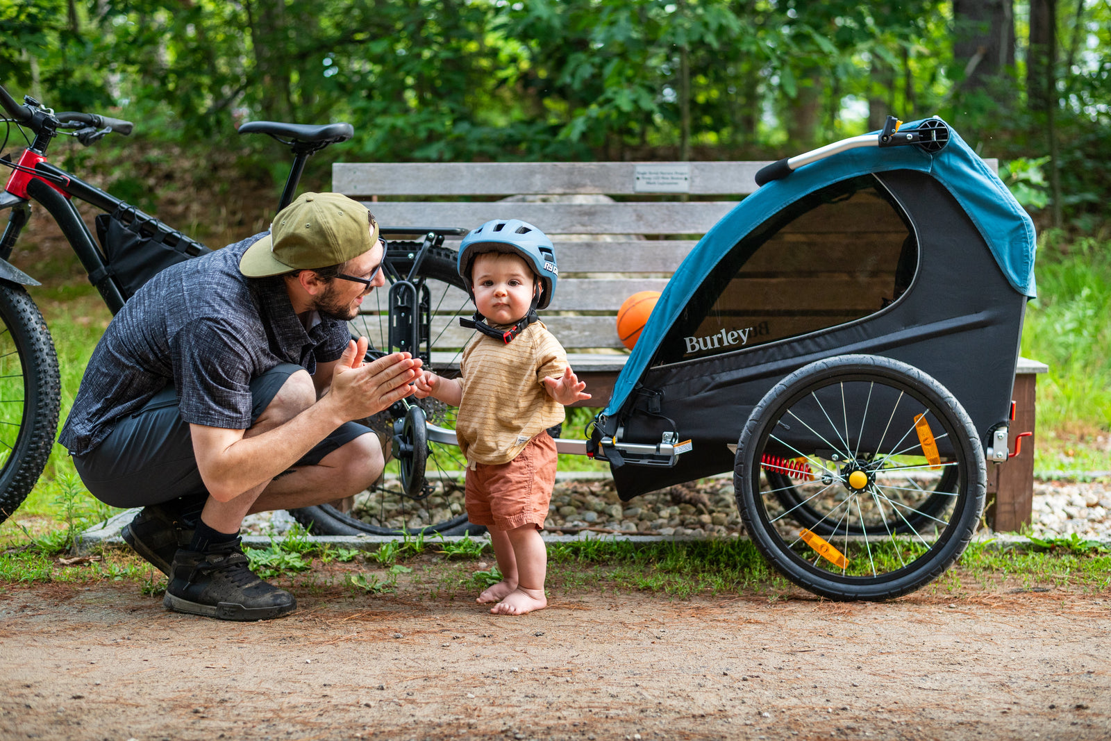 Man crouching in front of child with bike trailer