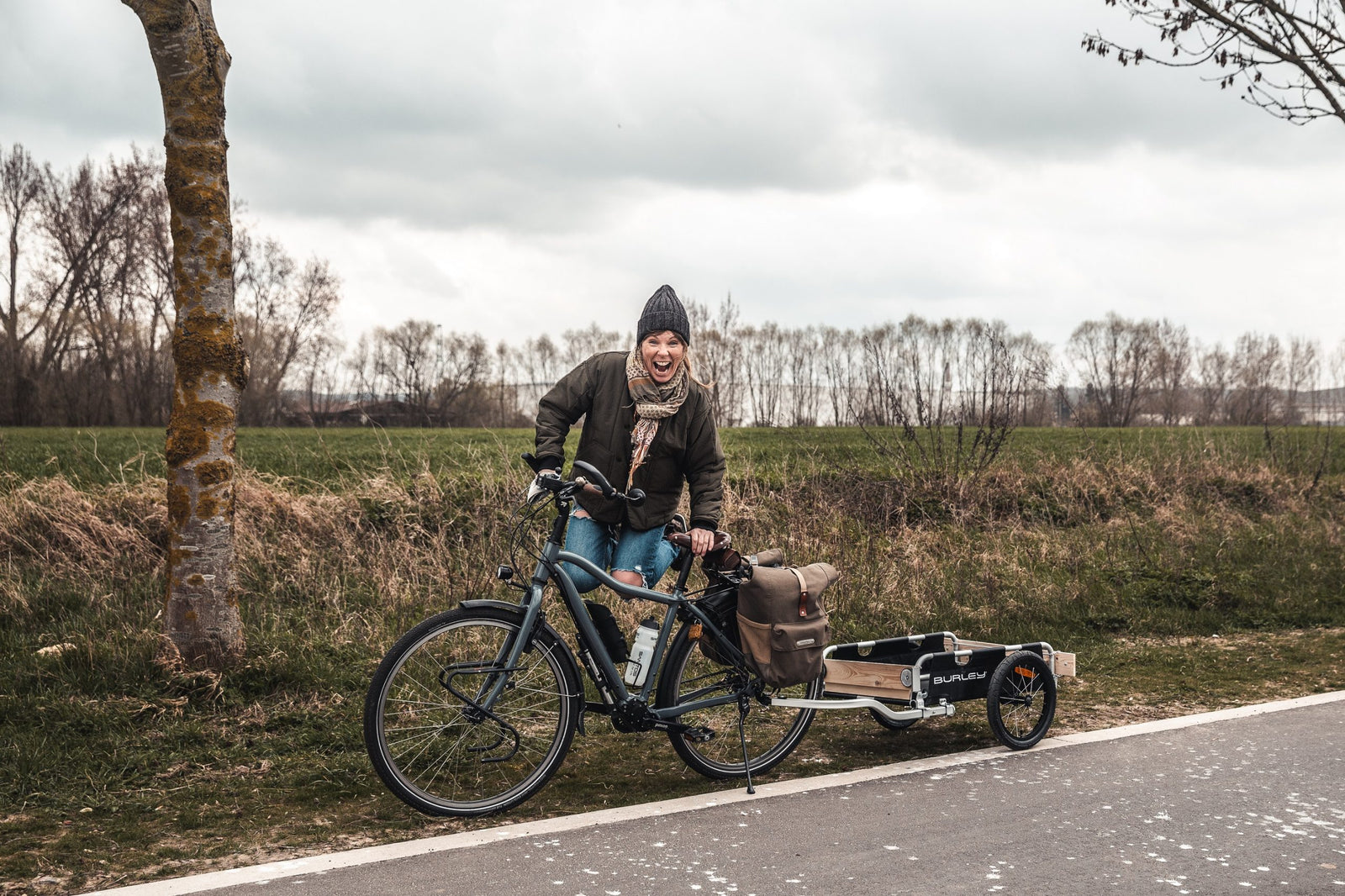 woman jumping and smilign near bike with Flatbed cargo trailer