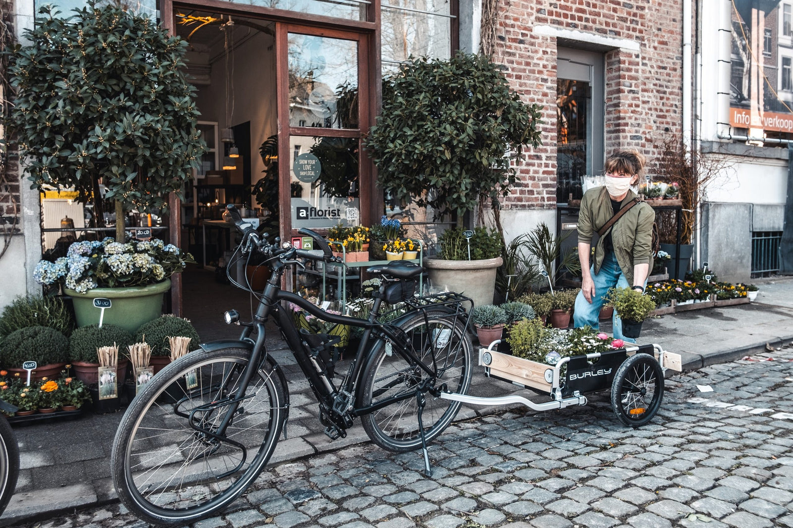 woman loading plants into flatbed cargo bike trailer