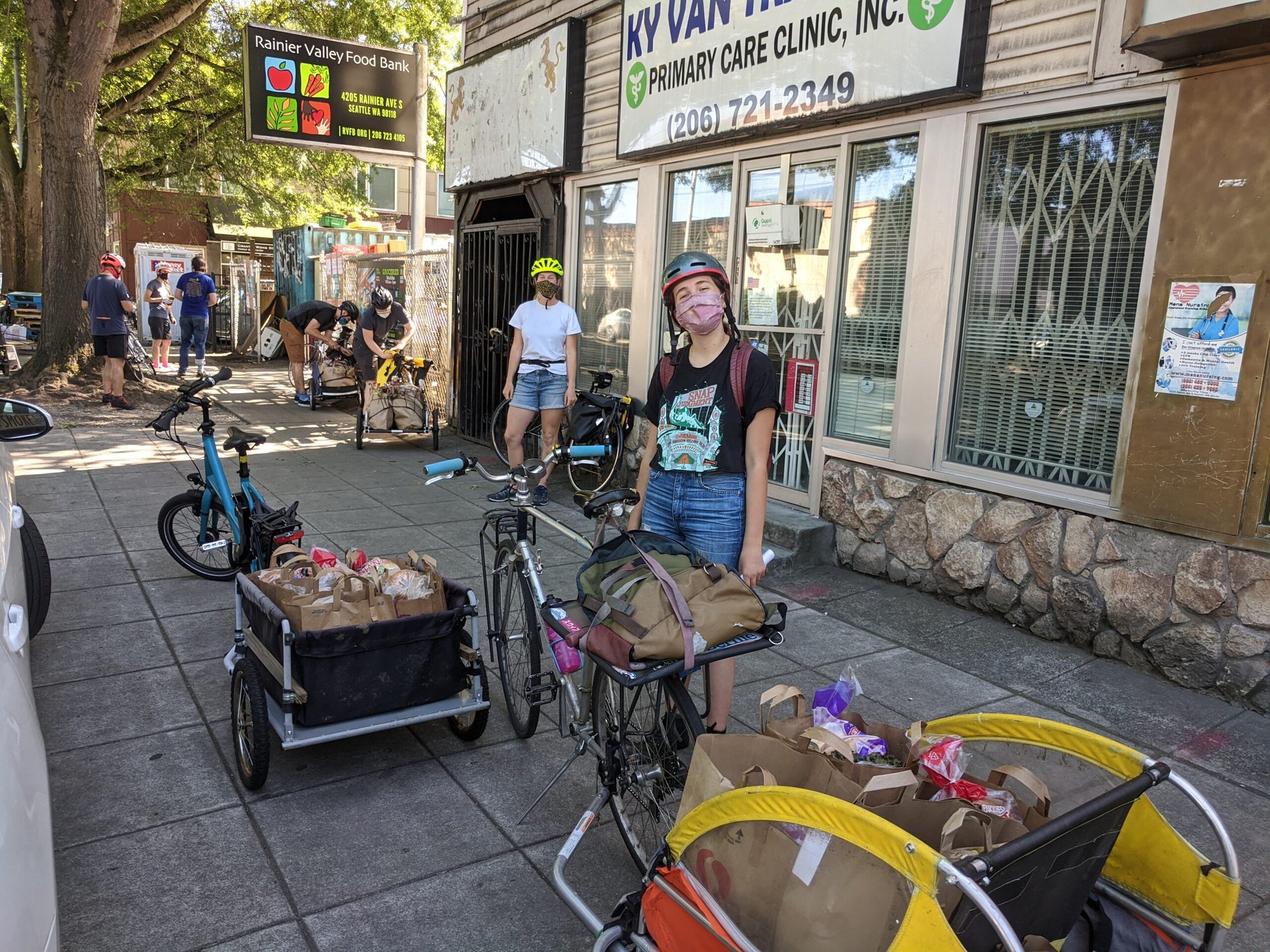 woman stands between bike trailers loaded with boxes of food for food pantry delivery