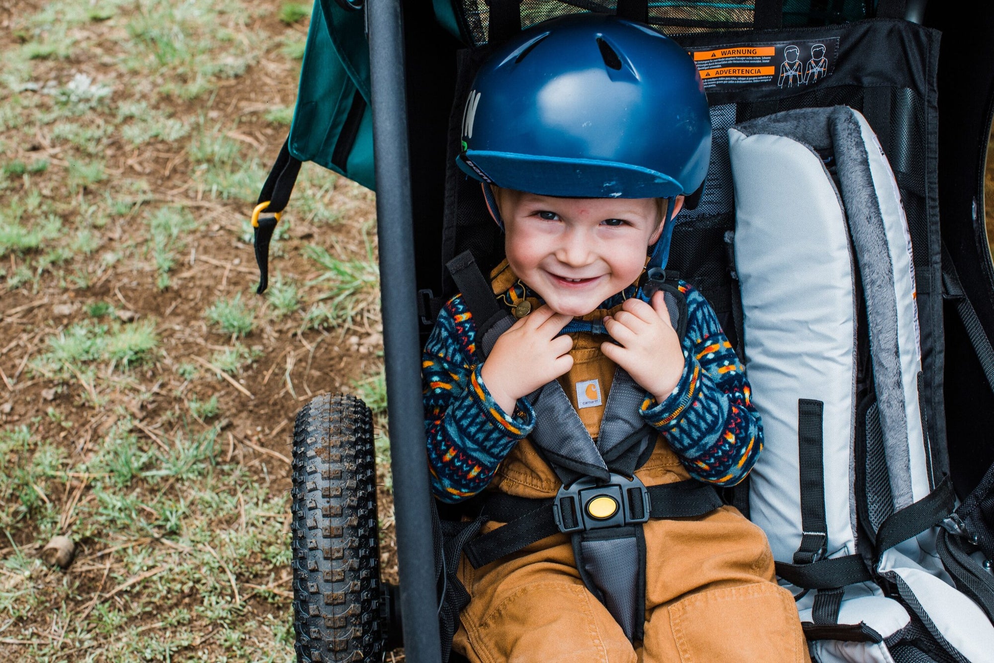 toddler boy sitting in kid bike trailer smiling