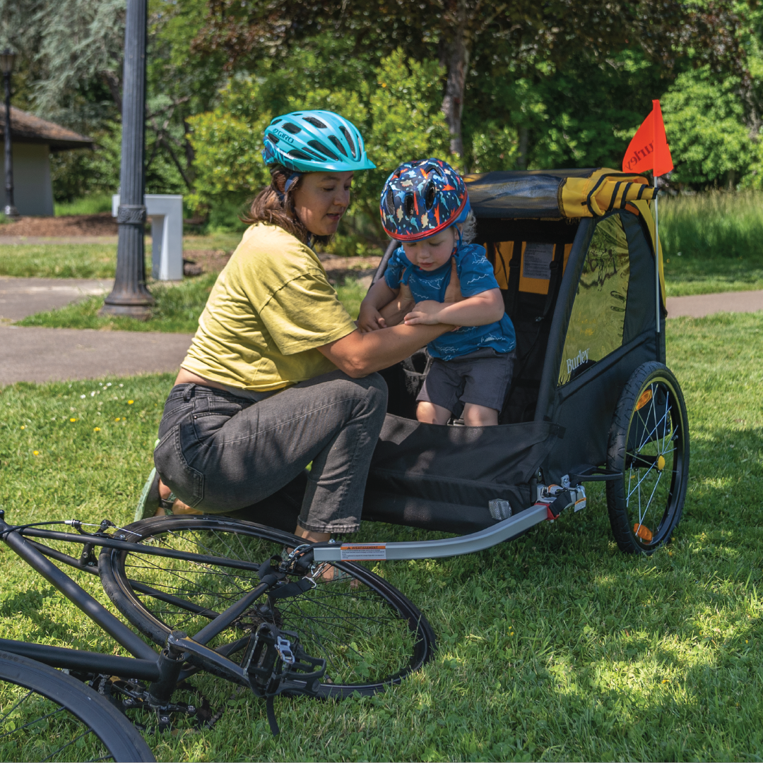 Parent helping child exit a Burley Bee Kid Bike Trailer.