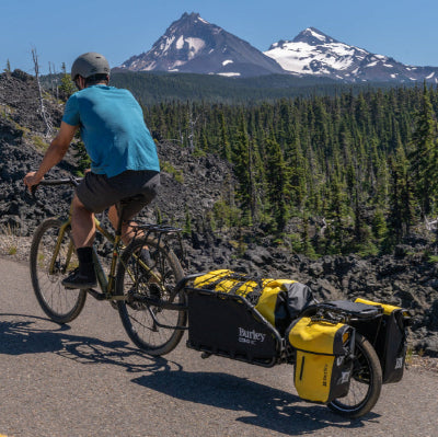 Person riding a bicycle with a Burley Coho XC in a mountainous landscape