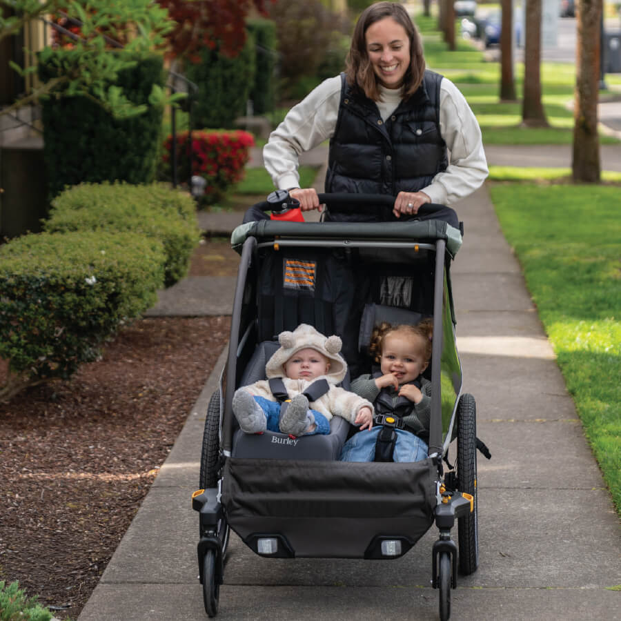 Mother strolling two children in D'Lite X with 2-Wheel Stroller kit.