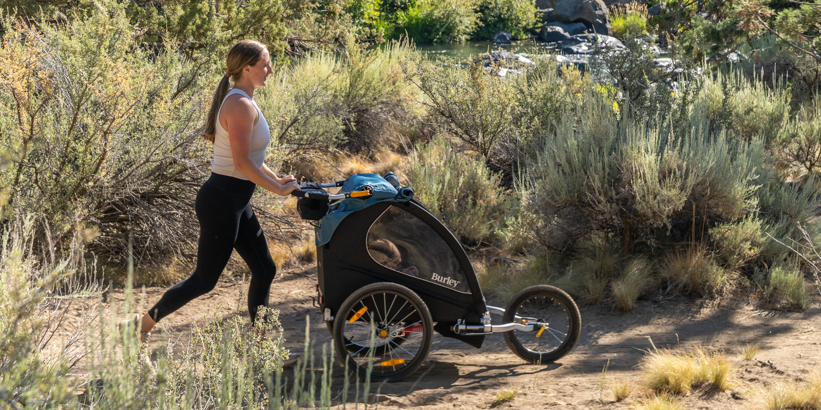 Woman jogging with Encore X and Jogger Kit on a river path