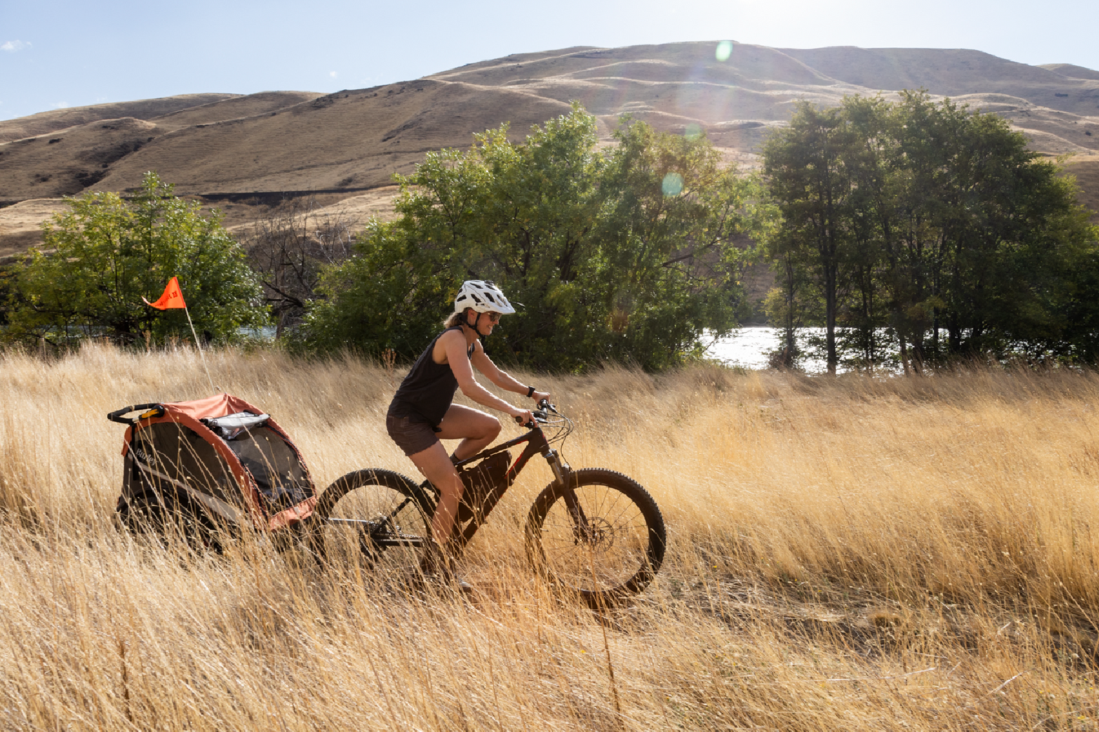 Mother biking with child in Burley Cub X trailer on wilderness trail